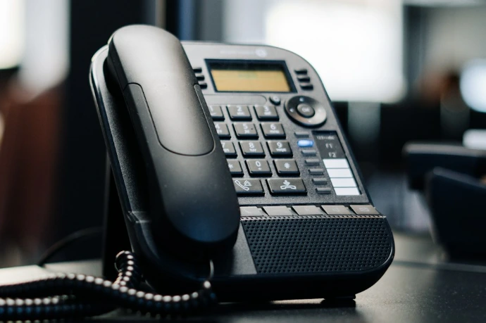 black ip desk phone on black wooden table